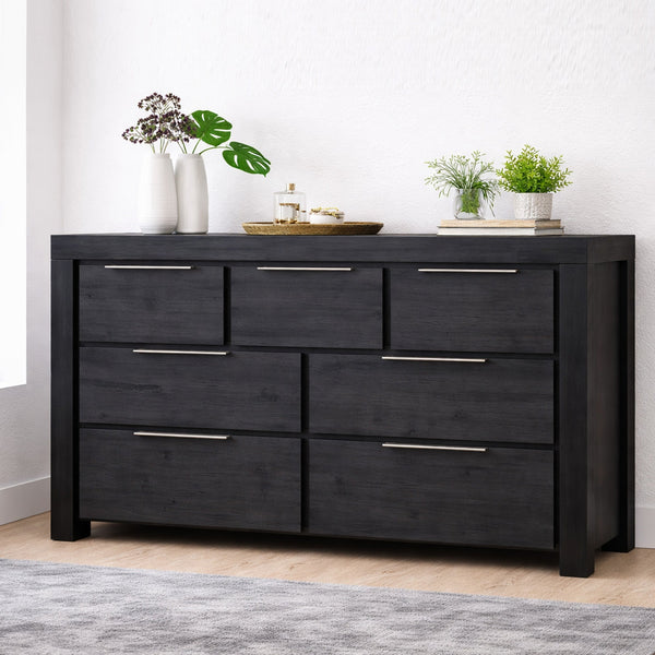 Black dresser with silver handles in a room with plants and decor.