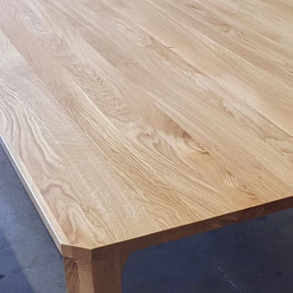 Light wood dining table corner with tapered leg and visible joinery