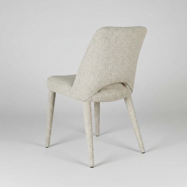 An upholstered dining chair with a textured light beige fabric and tapered legs, shown from a three-quarters angle on a white background.