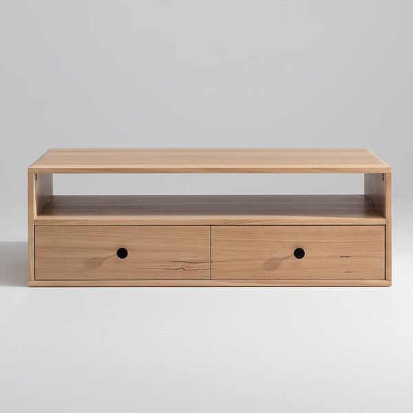 Light wood coffee table with two drawer fronts, black round knobs, and open top shelf