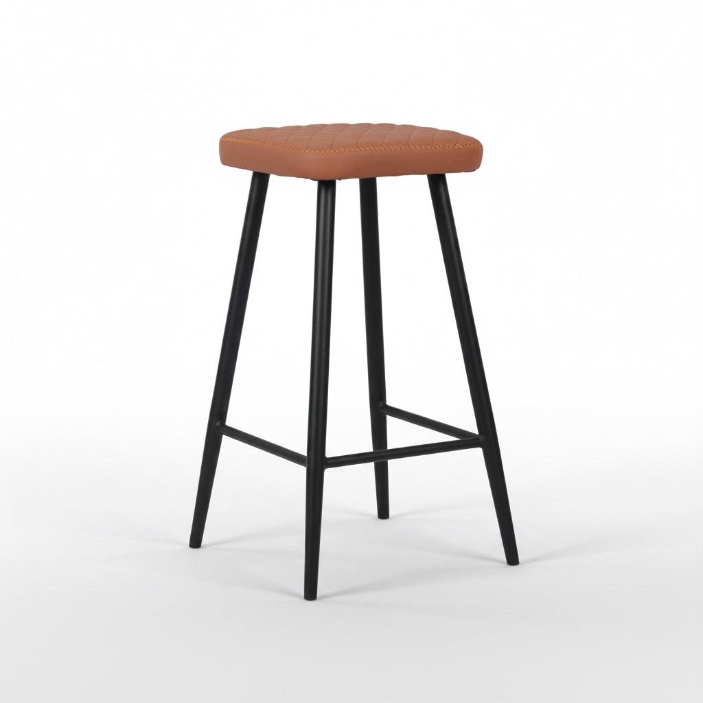 Tan padded bar stool with round seat, tapered black legs, and lower footrest