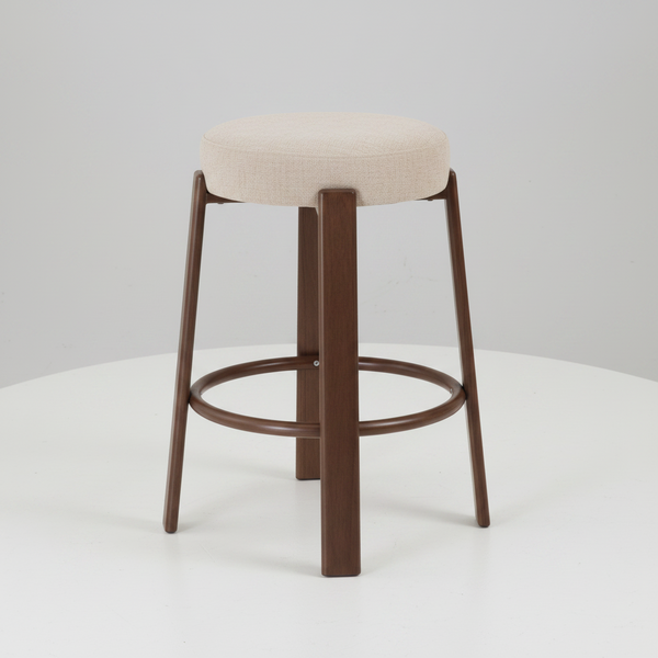 A modern bar stool with a round beige upholstered seat cushion and a dark brown wooden frame, shown on a clean white circular platform against a light gray background.