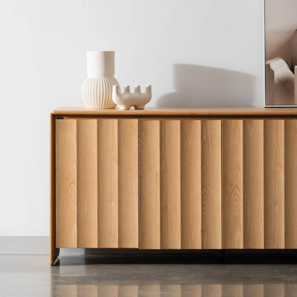 Light wood buffet cabinet front with vertical doors and decor on top