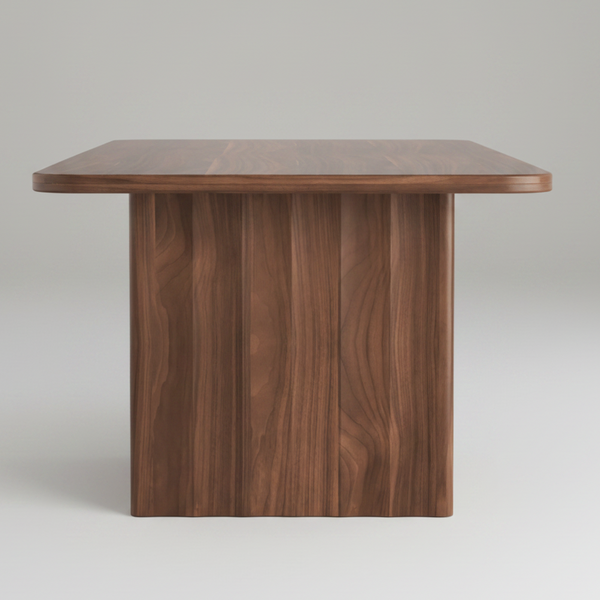 A modern wooden table with a rectangular top, rounded corners, and a thick pedestal base, shown on a plain white background.