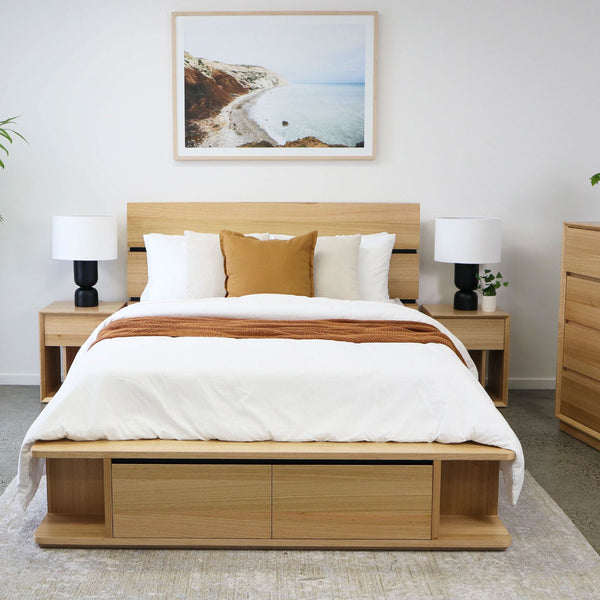 Wood queen-size bed frame with panel headboard and white bedding with tan throw