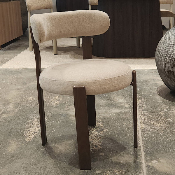 Beige upholstered dining chair shown from side angle with walnut frame and armrests