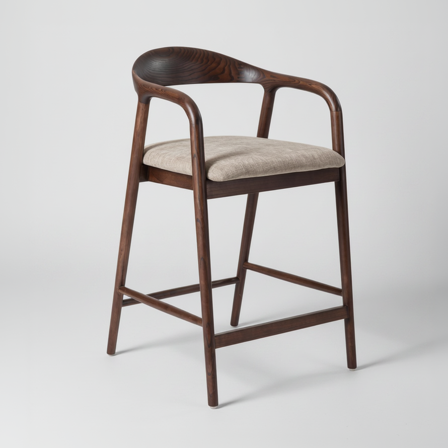 The Carvo Bar Stool combines modern simplicity with everyday comfort, making it a stylish addition to kitchen islands and bar spaces. Crafted from solid ash wood, it is available in both natural oak and dark walnut finishes, complemented by a soft beige fabric seat. Featuring a curved backrest with integrated arm support and a clean, timeless silhouette, the Carvo Bar Stool brings warmth and sophistication to contemporary interiors.