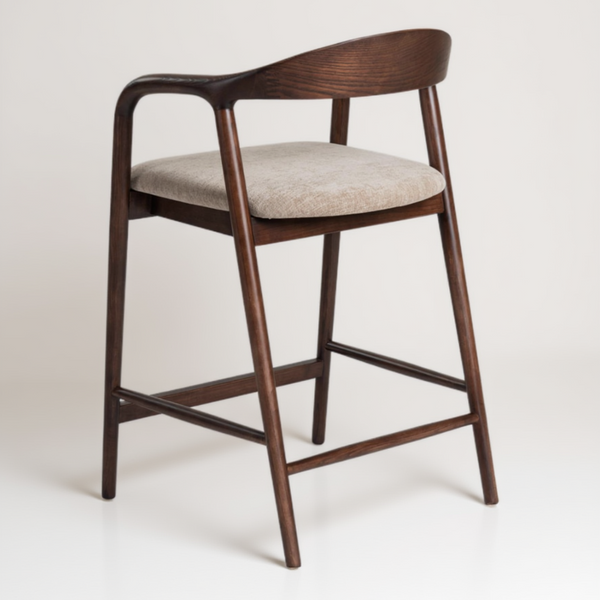 A modern counter stool with a curved dark brown wooden frame, armrests, and a light beige upholstered seat cushion, shown against a plain white background.