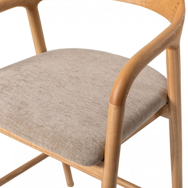 A close-up of a modern wooden dining chair with a curved natural oak frame and a textured beige fabric seat cushion, shown against a plain white background.