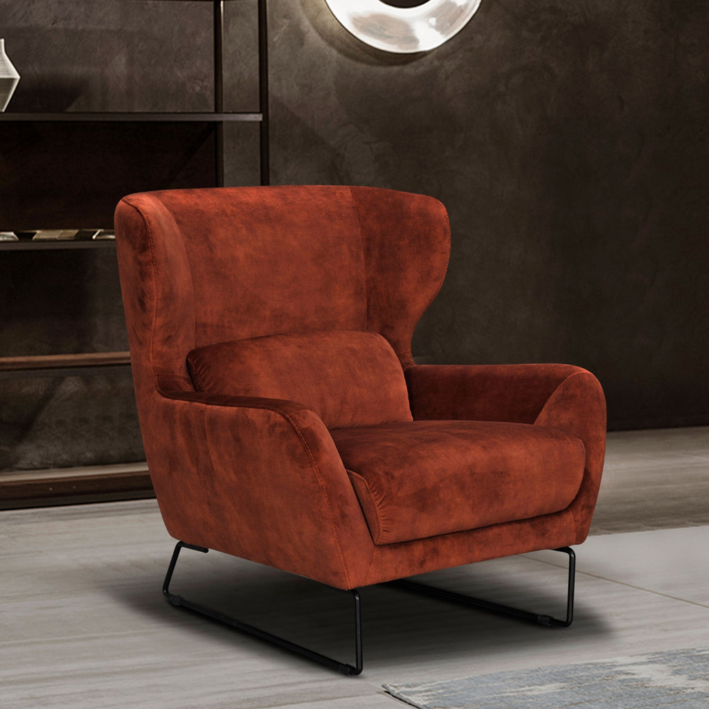 Rust velvet accent chair with rounded arms, low back, and black metal legs