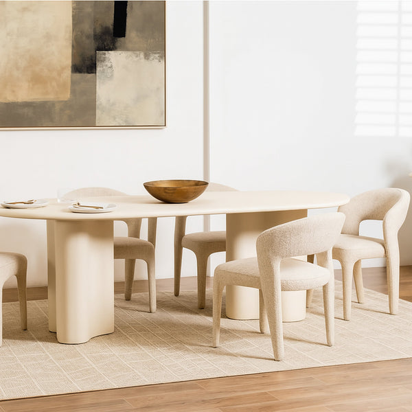Oval white dining table with beige upholstered armchairs and plates