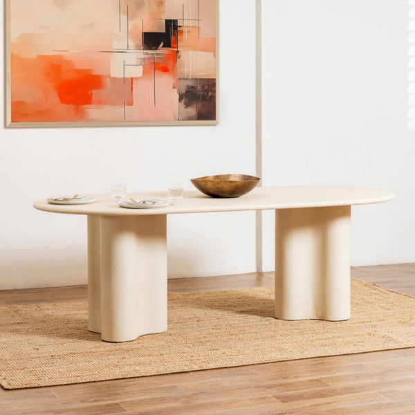 Beige dining table with a bowl on a wooden floor in a room with abstract art on the wall.