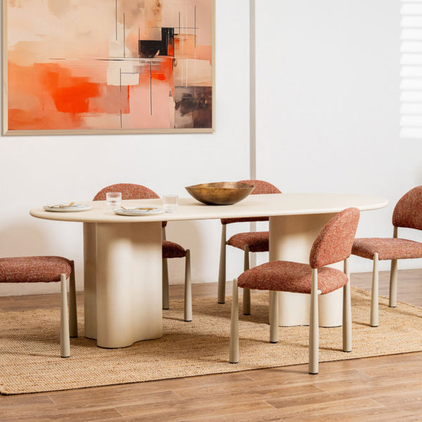 Dining room with a white oval table and red chairs, abstract painting on the wall.