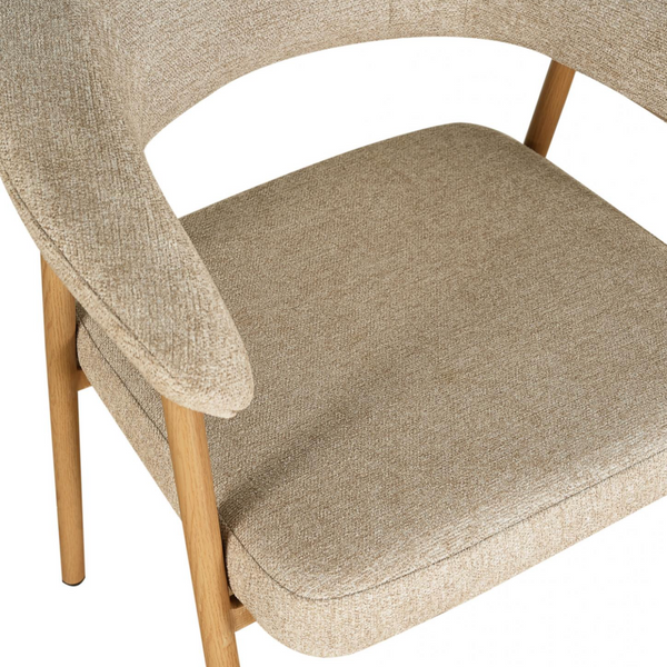 Close-up of a modern upholstered armchair with a textured beige fabric seat, curved armrests, and light natural wood legs on a white background.