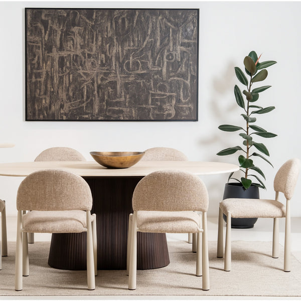 Dining room with a round table and chairs, abstract painting on the wall, and a plant.