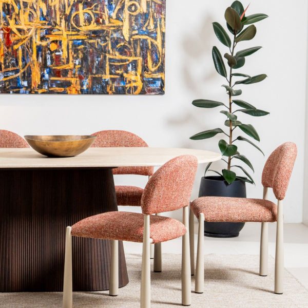 Dining table with orange upholstered chairs and dark ribbed pedestal base