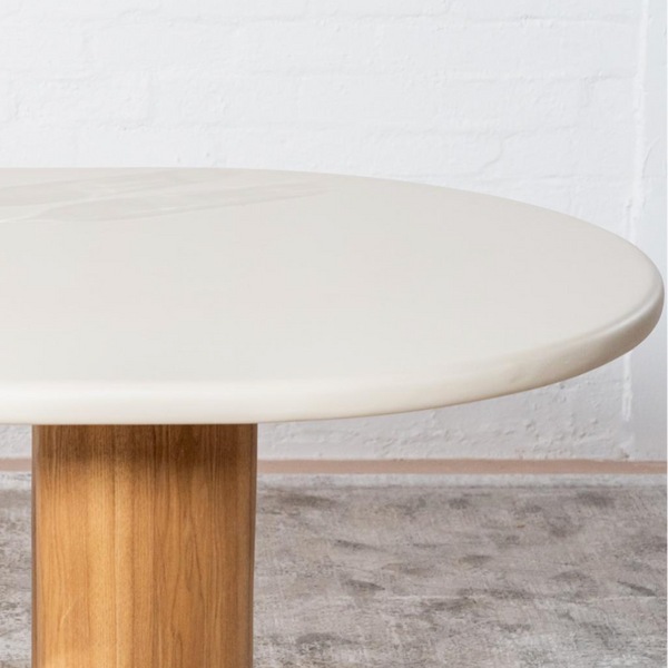 Round dining table with cream tabletop and light wood pedestal base