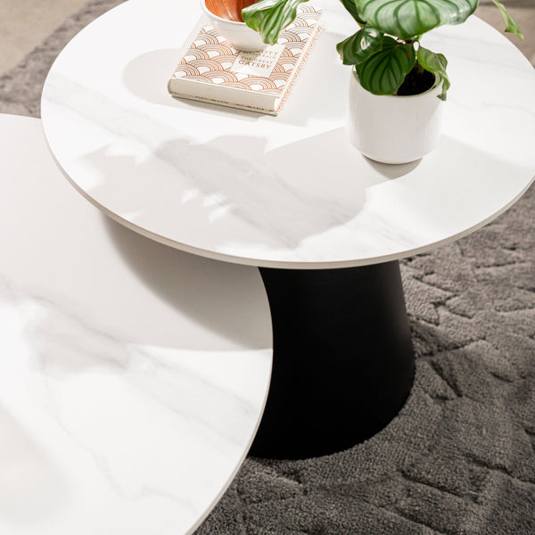 Round white side table with black tapered pedestal base, angled view
