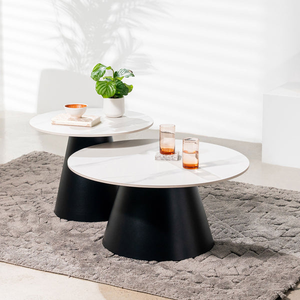 Round white marble-top nesting tables with black tapered pedestal bases