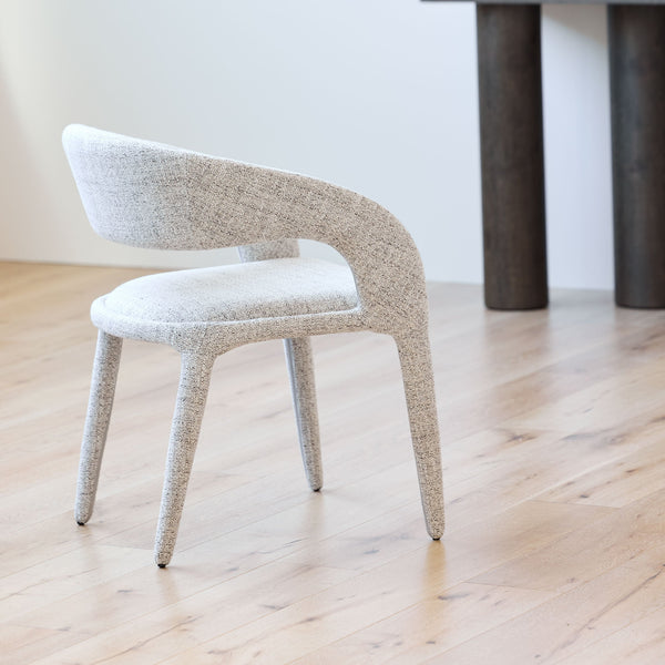 Upholstered dining chair with arched backrest, padded seat, and slim tapered legs