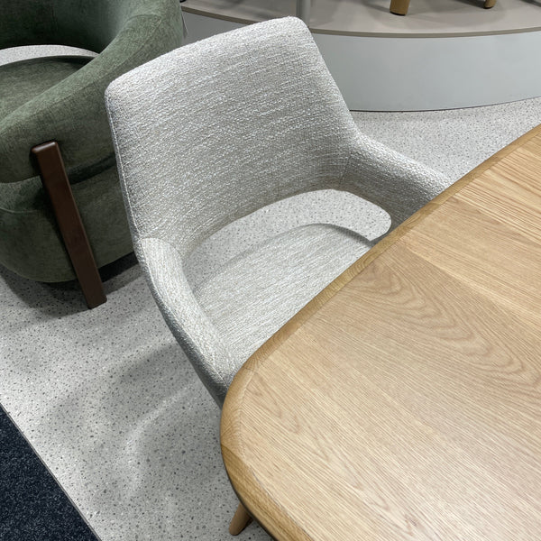 Oatmeal tweed swivel dining chair with wooden legs and curved armrests, side view