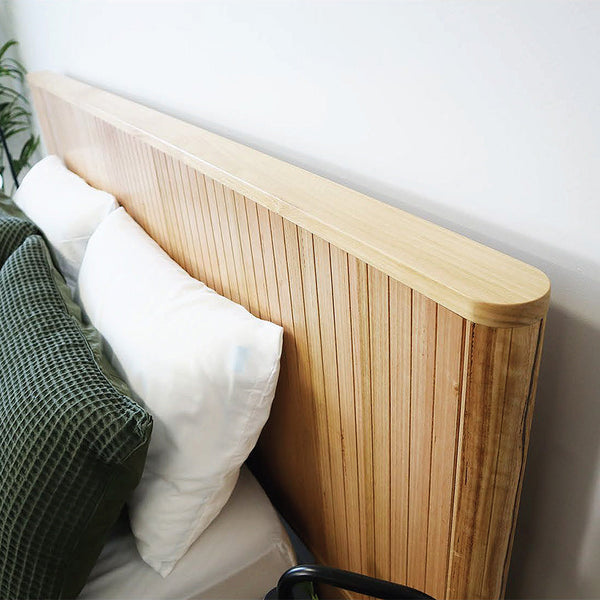 Wood slat headboard with dark green bedding and two white pillows