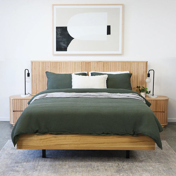 Queen/king size bed set with green textured quilt, white and green pillows on wood frame