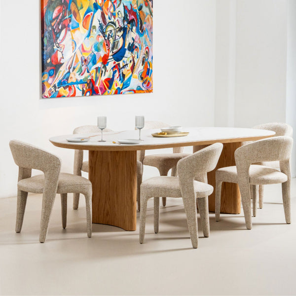 Round dining table with natural wood pedestal base and light upholstered dining chairs