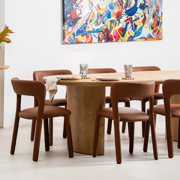 Tan dining chairs with rounded upholstered back and seat, tapered wooden legs around a table