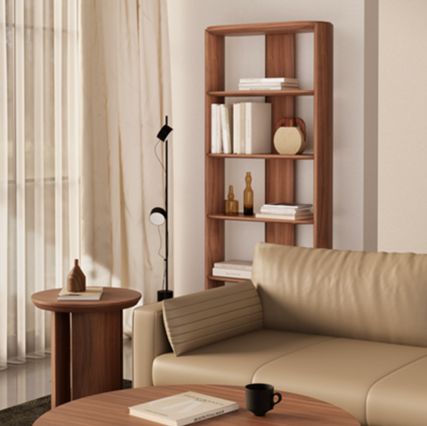 A tall, modern wooden bookcase with five open shelves stands in a styled living room next to a beige leather sofa, a round wooden side table, and a floor lamp.