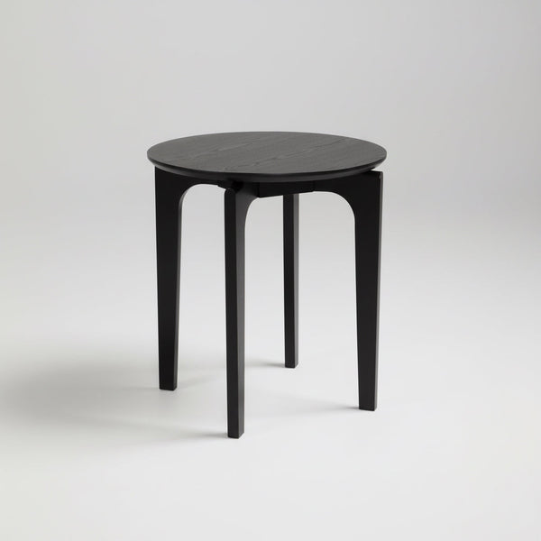 Round black coffee table with circular top and four tapered legs