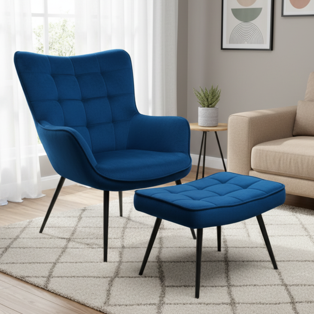 A modern blue upholstered armchair with a matching ottoman in a bright living room setting with a beige sofa, white curtains, and a patterned rug.
