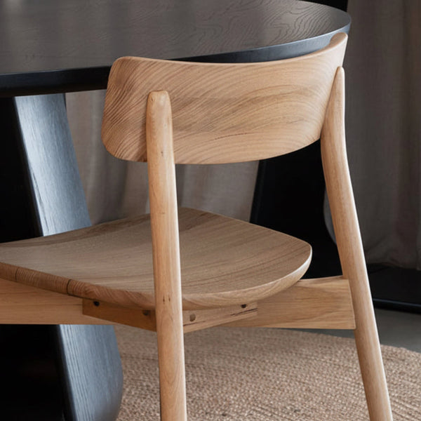 Wood dining chair close-up with curved arms, solid seat, visible wood grain