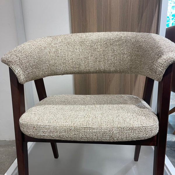 A close-up of a mid-century modern chair with a dark brown wooden frame and textured beige bouclé upholstered seat and backrest cushions.