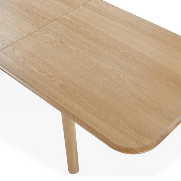 Light wood dining table top corner with rounded edge and visible grain
