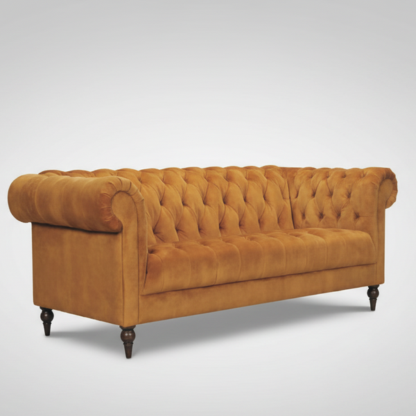 Warm brown velvet Chesterfield sofa angled view with button tufting and dark turned legs