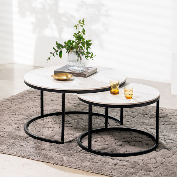 Two round nested tables with white marble-look tops, black frames, and open circular shelves