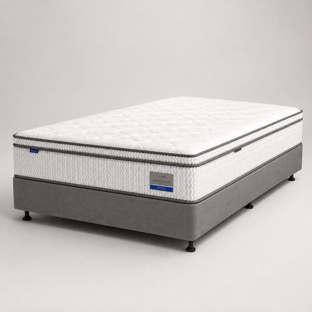 A mattress on a gray upholstered bed base, photographed in a clean studio setting against a light gray background.