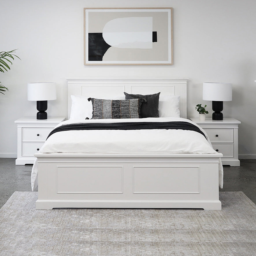 White paneled bed frame with pillows and matching nightstands