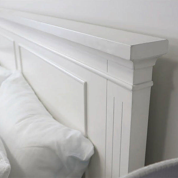 White paneled headboard with vertical trim and bed sheet corner