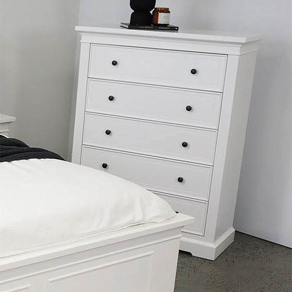 White dresser with stacked drawers and round black knobs beside bed